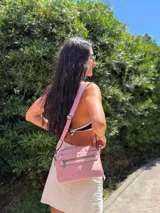 Bandolera de diseño moderno y funcional, confeccionada en nylon color marrón claro. Cuenta con múltiples compartimentos con cierre metálico, herrajes plateados y una correa ancha ajustable con detalle de marca.