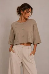 Blusa cropped de manga corta y corte amplio, color beige, con aplicaciones de pedrería y perlas distribuidas por toda la prenda.