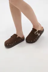 Suecos negros de estilo zueco con capellada de cuero sintético, detalle de hebilla metálica dorada y tachas decorativas alrededor de la suela. Poseen plantilla ergonómica y suela de plataforma dentada.