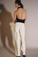 Top de cuello halter con escote fluido y caída suave. Presenta cierre con botones en la parte posterior y diseño sin mangas.