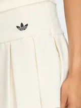 Falda mini de estilo tenista color blanco, con diseño plisado y talle bajo. Presenta el logo de la marca bordado en la parte frontal y cierre lateral.