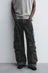 Pantalón cargo de denim lavado negro, corte relajado y tiro medio. Presenta múltiples bolsillos cargo con solapa y detalle de cierre en las perneras, además de bolsillos de vivo traseros. El bajo es ajustable con trabilla.