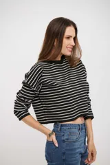 Buzo corto de tejido de punto con diseño a rayas horizontales blancas y negras, cuello redondo y mangas largas.