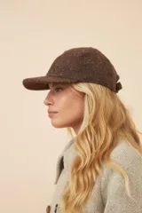 Gorra con visera confeccionada en lana fina sin teñir, con un sutil patrón de tejido en espiga.