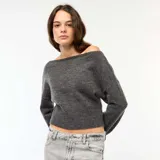 Sweater de punto gris oscuro, con escote Bardot (hombros descubiertos), manga larga y puño y ruedo acanalados. El calce es corto y holgado.