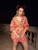 Conjunto de dos piezas compuesto por un top corto de mangas abullonadas con elástico y una falda corta con volados, ambos confeccionados en tela estampada a rayas multicolores.