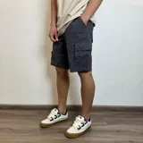 Bermuda cargo gris oscuro de gabardina, con bolsillos laterales y traseros con solapa.