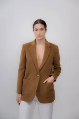 Blazer color camel de baby alpaca, con cuello de solapa, cierre frontal con botones y bolsillos laterales.