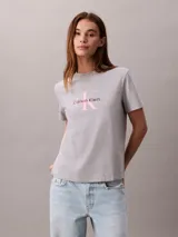 Remera gris melange de corte regular y manga corta, con cuello redondo y el logo de la marca en el pecho con letras rosadas y marrones.