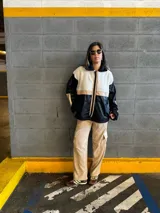 Campera con cuerpo de corderito color beige, mangas y parte inferior de cuero sintético negro con textura tipo cocodrilo. Tiene cuello estilo camisa con solapas de corderito negro, cierre frontal con cremallera y bolsillos laterales.