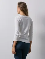 Cardigan blanco de tejido fino con abertura central y botones.