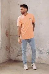Remera color durazno de corte recto y manga corta, con cuello redondo y pequeño bordado de dos patos en el pecho.