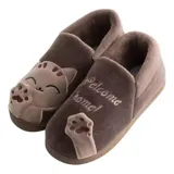 Pantuflas cerradas de color azul con diseño de gatito, confeccionadas en piel sintética suave con interior de peluche gris. Presentan un bordado con la frase 'Welcome Home' y apliques de patitas de gato. Cuentan con suela de goma antideslizante.