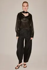 Blusa de seda color marrón oscuro con estampado geométrico sutil. Presenta un diseño de cuello fluido tipo pañuelo, manga larga con puños anchos y una caída suave y elegante.