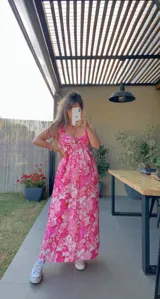 Vestido largo de lino con estampado floral en tonos rosados, con breteles finos y corte debajo del busto.