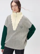 Pullover de tejido acanalado grueso con diseño bicolor en tonos marrón y bordó. Presenta cuello alto con cierre frontal, mangas largas y corte holgado.