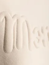 Buzo de algodón color crema, de cuello redondo y manga larga, con logo bordado en el frente.