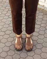 Sandalias de cuero gamuzado color marrón, tipo romanas, con tiras entrelazadas, talón cerrado y tira ajustable con hebilla metálica en el tobillo.