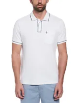 Polo blanco de manga corta con cuello clásico, tapeta de botones y bolsillo en el pecho. Presenta vivos en azul marino en cuello y mangas, y logo de pingüino bordado en el bolsillo.