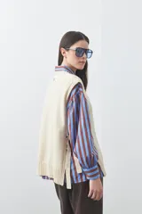 Chaleco tejido de punto con silueta relajada y diseño sin mangas. Presenta lazos laterales ajustables y cuello redondo.