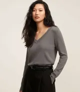 Suéter de punto color amarillo, con escote en V y mangas largas. Presenta un diseño básico y versátil, confeccionado en una mezcla de viscosa, poliamida y elastano.