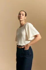 Remera de rib color beige, con cuello redondo y mangas cortas amplias con leve frunce en los hombros. Confeccionada en tejido elastizado de textura acanalada.