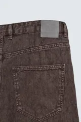 Pantalón de corte baggy fit confeccionado en tejido de algodón con textura y efecto lavado. Presenta diseño de cinco bolsillos, cierre frontal con cremallera y botón.