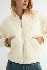 Campera tipo bomber con frente acolchado en diseño de rombos y mangas de tejido de punto acanalado. Presenta cierre frontal metálico y cuello, puños y ruedo en tejido elástico.