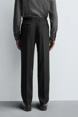 Pantalón de traje regular fit confeccionado en tejido de lana. Presenta bolsillos frontales, bolsillos traseros de vivo con botón y cierre frontal con cremallera y botón.