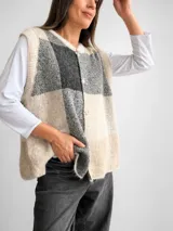 Chaleco de tejido de punto con diseño de cuadros grandes en tonos beige y gris. Presenta un corte oversize, cuello redondo y cierre frontal con botones a tono.