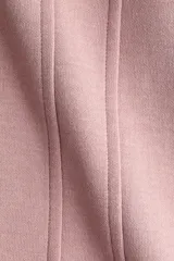 Remera de punto interlock pesado en color rosado, con cuello redondo y mangas cortas. Presenta cintura entallada con pinzas moldeadoras en la parte delantera que generan un sutil efecto peplum.