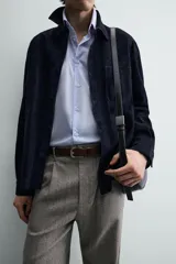 Sobrecamisa de hombre, color azul marino oscuro, confeccionada en piel con acabado ante. Presenta cuello solapa, manga larga con puños abotonados, un bolsillo de parche en el pecho y cierre frontal de botones.