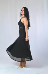 Vestido largo negro con escote halter y textura calada. Presenta un corte en la cintura con transparencia y un ruedo con detalle calado que deja ver la pierna.