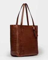 Bolso shopper negro de cuero con textura de cocodrilo, doble asa de hombro y dije colgante rectangular.