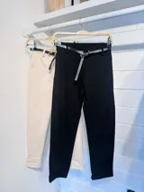 Pantalón de corte recto y tiro medio en color blanco, confeccionado en tejido elástico. Presenta cierre frontal con botón y cremallera, bolsillos laterales y viene acompañado de un cinturón fino de cuero sintético negro con hebilla metálica.