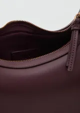 Riñonera de efecto piel color bordó, con diseño estructurado de líneas curvas, cierre de cremallera y asa ajustable con hebillas y herrajes metálicos dorados.
