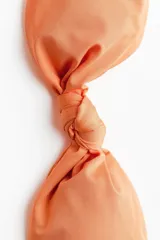 Top de bikini strapless color salmón con un nudo decorativo en el centro, copas con relleno extraíble y varillas laterales.