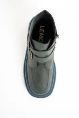 Bota corta de cuero color verde oscuro, con suela track gruesa de color celeste. Presenta dos correas ajustables con hebillas metálicas plateadas y un pequeño dije de estrella dorada en el lateral. Tiene cierre de cremallera en el interior.