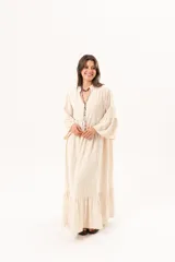 Vestido largo beige de silueta oversize, confeccionado en tela ligera con textura y motivos bordados tono sobre tono. Presenta escote en V, mangas amplias con volados y un gran volado en el ruedo.