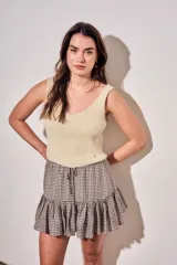 Minifalda con estampado de cuadros vichy en tonos marrón y blanco, con cintura elástica fruncida, cordón ajustable y volado en el ruedo.