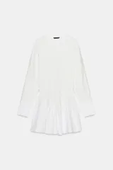 Vestido corto blanco con cuello redondo y manga larga tipo murciélago. El bajo tiene un acabado voluminoso con tejido combinado a tono y cierre frontal con botones.