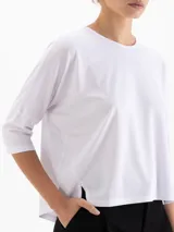 Remera de silueta relajada confeccionada en tela de punto suave. Presenta escote redondo, mangas 3/4, recorte estratégico en la espalda y tajos laterales que aportan movimiento y una caída fluida.