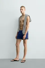 Short de baño azul con cintura elástica ajustable con cordón, bolsillos laterales y ribetes en contraste en los bordes.