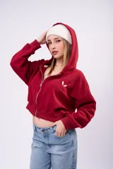 Campera cropped de color marrón con cierre frontal completo, capucha y mangas largas. Presenta un pequeño bordado blanco en el pecho y un diseño holgado.