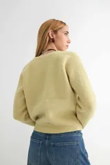 Cardigan negro de tejido de punto, con escote en V, manga larga y cierre frontal con tres botones dorados grandes.