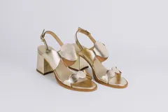 Sandalias doradas de cuero con taco cuadrado y diseño de ondas en el empeine y en la puntera. Cierre con hebilla en el tobillo.