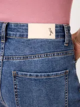 Short de denim elastizado de tiro alto, color beige, con bolsillos delanteros y traseros, y cierre frontal con botón y cremallera.