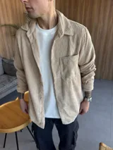 Sobrecamisa de pana color beige, con cuello clásico, cierre frontal de botones y un bolsillo en el pecho.