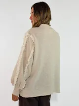 Sweater de punto color bordó, con cuello redondo, mangas largas abullonadas y detalle de flecos en las costuras de los hombros.