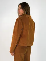 Chaqueta de pana color marrón, con solapas desflecadas, cierre frontal con botones y bolsillos delanteros con solapa desflecada.